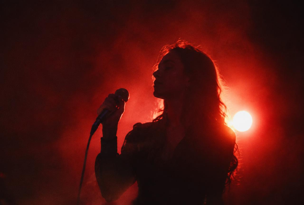 Singer performing under red stage light